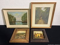 Four framed assorted wall art pieces displayed together on black surface