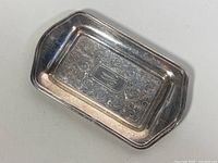 Top view of rectangular sterling silver tray with engraved floral scrollwork and a monogram in the center.