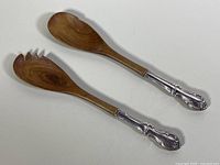 Full view of the wooden salad spoon and fork with sterling silver handles showing the overall form and condition.