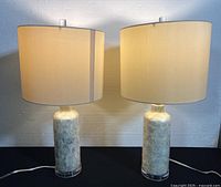 Front view of both lamps illuminated showing bases, shades and clear Lucite feet