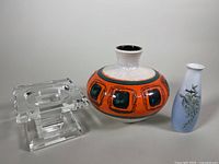 Three items shown together: clear crystal pillar candleholder, West German vase with orange and green pattern, Royal Copenhagen blue and white bud vase with floral design.