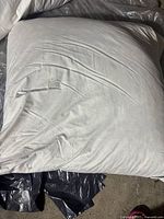 Photo of one large white pillow with visible fabric texture and some creases.
