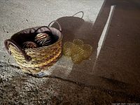 Small brown woven basket with 2 zebra print balls inside and 4 yellow hobnail glass votive candle holders placed beside the basket on the ground.