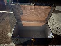 Open vintage blue storage trunk chest showing the interior fabric lining and metal reinforcements on corners, front side lock visible