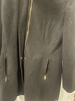Close-up view of gold zipper and zipper pulls on the black Calvin Klein men's jacket.