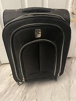 Front view of soft-sided black carryon suitcase showing multiple compartments and zippers with silver trim.