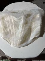 White corset style top laid flat showing front and structure with sheer overlay and boning