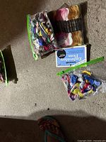 Photo showing multiple packs and bags of embroidery floss on floor with varied colors and brands visible