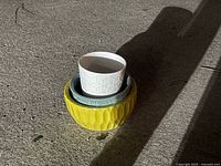Three ceramic flower pots nested together showing white, yellow and blue pots stacked.