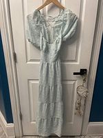 Front view of light blue Forever 21 dress with puff sleeves hanging on wooden hanger on white door