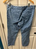 Front view of blue patterned men's pants hanging on a wooden hanger