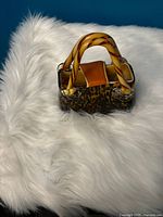 Front view of the glass mini handbag showing the tortoiseshell pattern and twisted amber glass handles.