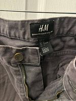 Close-up photo of the inside label showing the brand H&M and fit type 'Skinny Fit', size CA 32, made in Bangladesh.