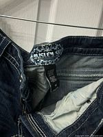 Close-up photo of the interior label with Paisley brand tag sewn into dark blue denim shorts.