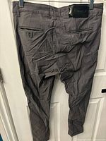 Back view of slim fit men's skinny jeans size 32 showing back welt pockets and black brand patch on waistband. Jeans appear heavily wrinkled.