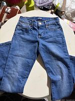 The layout of full blue denim slim pants showing front sides including leg width and stitching details.