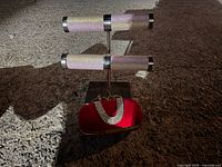 Snake style knuckle purse resting on the base of a silver-tone jewelry stand with two horizontal bars.