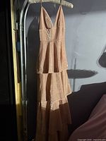 Full view of pink sleeveless dress hanging, showing tiered layers and overall length.