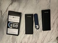Photo showing three Kensington branded black power banks, one small blue cylindrical power bank, and one HP phone case in original packaging.