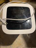 Top view of the black control panel showing timer, lock, and arrow buttons with white power cord and plug placed over it.