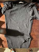 Black ribbed Zara bodysuit laid flat with gathered puff sleeves visible.