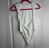 White open back bodysuit on a hanger showing front and side profile