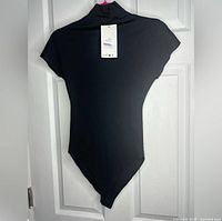 Full view of the Zara black silk bodysuit hanging, showing overall shape and material.