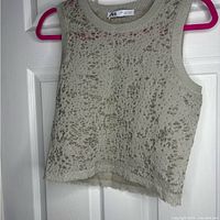 Front view of grey Zara tank top on pink hanger showing its texture and sleeveless design