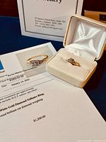 Ring in open jewelry box alongside appraisal certificate showing $1,200 valuation.