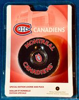 Photo of the sealed special edition Montreal Canadiens puck with embedded loonie coin in original Royal Canadian Mint packaging, showing front and text details.