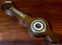 Full view of antique weather station showing wooden body with mounted barometer and thermometer.