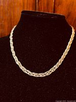 Thick trio-braided sterling silver necklace displayed on a black velvet neck stand showing front view.