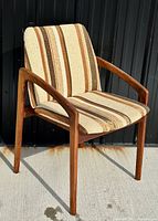 Front view of the vintage Danish Mid Century Modern teak chair showing the striped upholstery and teak wood frame with curved armrests.