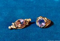 Pair of sterling silver amethyst rings displayed on blue fabric background, showing front view and detailing on the rings.