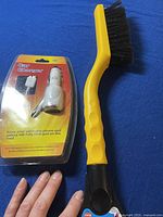 Samsung car charger in packaging and yellow car cleaning brush on blue background