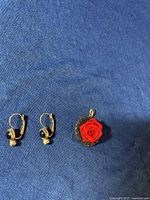 Photo showing pair of earrings with dark turquoise stones and felt red rose pendant.