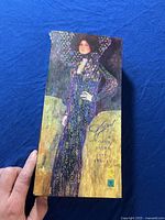 Box showing the full Gustav Klimt themed artwork of a woman in a decorated dress with gold background and title 'Klimt Color Light and Beauty'.