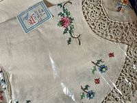 Close-up view of hand embroidered floral designs on the table skirt with lace trim visible.