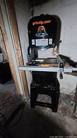Front view of band saw mounted on stand, table with fence and miter gauge