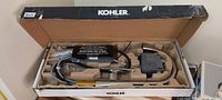 Photo of Kohler Annessia touchless pulldown kitchen faucet in original packaging, showing faucet, sensor module, and hose fittings.