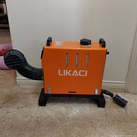 Full view of orange Likaci diesel portable heater showing black vent pipe, handles, and fuel cap on top.