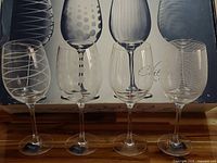 Photo showing set of 4 clear etched Mikasa wine glasses with various modern etched designs on bowls, standing on a flat surface with original box