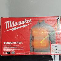 Closed box of Milwaukee M12 ToughShell Heated Jacket Kit showing packaging and product details including size Large and gray color.