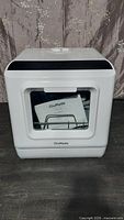 Front view of white ChuMaste portable countertop dishwasher, shows front door with window and manual inside.