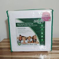 Photo of packaged Safeguard King size mattress protector mattress pad with label showing product features.