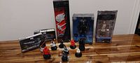 Full lot of Star Wars items on wooden table: 3 boxed action figures and 7 character tokens mostly in red and black.