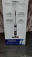 Front of box showing Tineco iFloor 3 Breeze Complete branding, 1-step cleaning, cordless and lightweight, self-cleaning, plus extra accessories section.