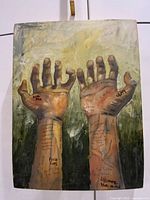 Front view of the signed oil painting on board showing two raised hands with social justice messages written on them.