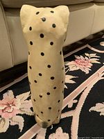 Front and side view of vintage hand-carved wooden feline figurine, cream color with black spots, painted eyes, nose and mouth.