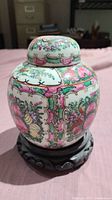 Porcelain ginger jar with lid on wooden stand, showing colorful detailed designs